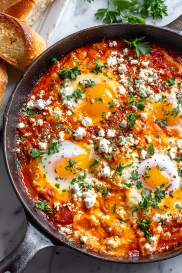 Cozy shakshuka with poached eggs in spiced tomato sauce, perfect for sharing this autumn.