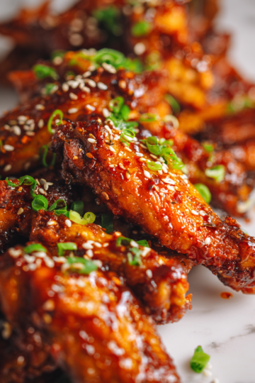 Baked sweet and spicy chicken wings topped with green onions and sesame seeds, ideal for parties and game nights, flavorful crowd-pleaser recipe.